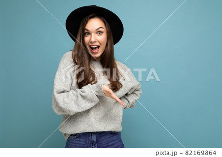 Photo of beautiful brunette happy joyful young woman directing finger to the side with copy space 82169864