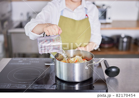 キッチンで料理をするエプロン姿の若い女性 82170454