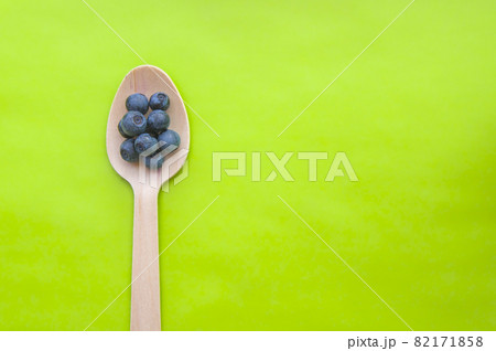 Flat lay of recycled spoon and juicy, fresh blueberries on color table. Space for text. Isolated ripe sweet bilberry fruits in eco spoon on green background. Copy Space. Healthy raw vegetarian food  82171858
