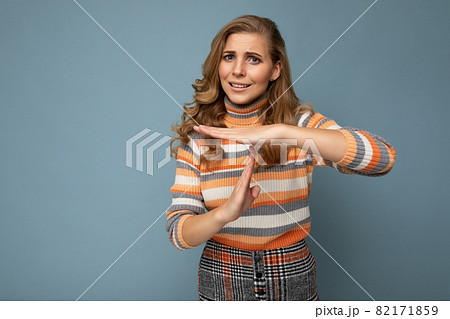 Portrait of young beautiful blonde curly woman with sincere emotions wearing stylish striped sweater 82171859