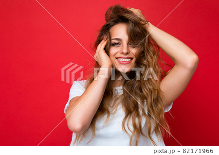 Young beautiful blond woman wearing white t-shirt looking at camera. Positive female shows facial Young beautiful blond woman wearing white t-shirt looking at camera. Positive female shows facial 82171966