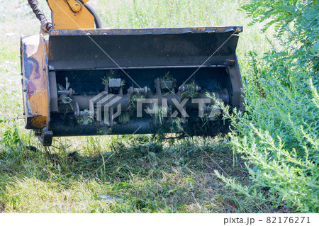 Wheeled tractor lawn mower with a external detachable mounted mower equipment driving on roadside of a suburban highway 82176271