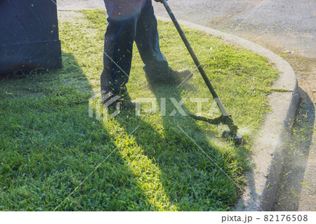 The gardener man mows the grass with a hand lawn mower. The gardener man mows the grass with a hand lawn mower. 82176508