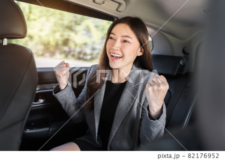 cheerful successed business woman sitting at the back seat of car 82176952