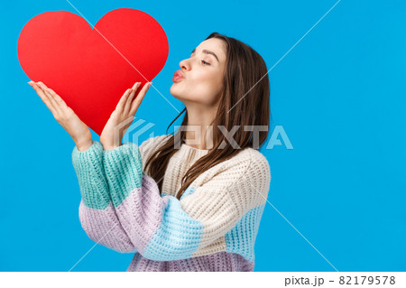 Dreamy young woman cherish her relationship, prepare valentines day gift, kissing big cute red heart sign over left side copy space, standing blue background delighted and upbeat Dreamy young woman cherish her relationship, prepare valentines day gift, kissing big cute red heart sign over left side copy space, standing blue background delighted and upbeat 82179578