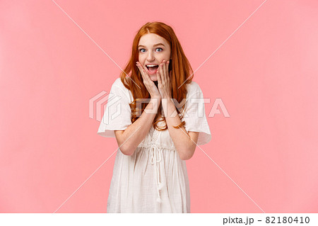 Expectation, anticipation and happiness concept. Amused cute redhead silly girl looking surprised and excited, gasping fascinated, looking charmed and amazed camera, pink background 82180410