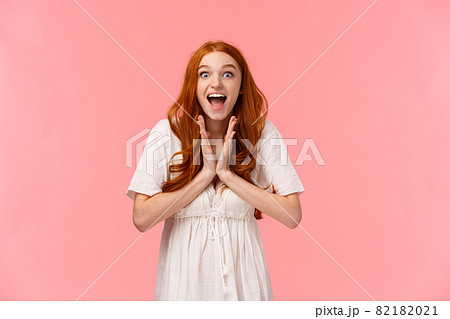 Fascinated, amused lucky redhead female in white dress, clap hands, applause from excitement and amazement, look camera astonished, feeling upbeat, winning prize, pink background 82182021