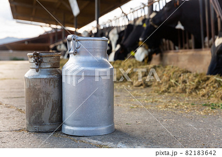 Aluminum milk cans standing outdoors in open cowshed Aluminum milk cans standing outdoors in open cowshed 82183642