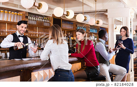 Portrait of barman and people who are standing near bar counter in luxurious restaurant Portrait of barman and people who are standing near bar counter in luxurious restaurant 82184028