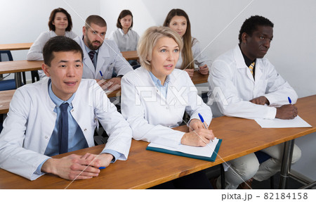 people attentively listening and making notes people attentively listening and making notes 82184158