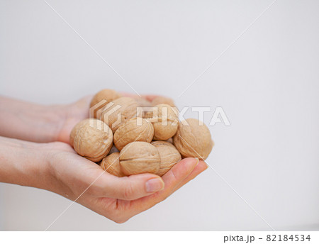 A lot of whole walnuts in women's hands on a white background close-up. Healthy, organic food with a high content of protein and protein. A lot of whole walnuts in women's hands on a white background close-up. Healthy, organic food with a high content of protein and protein. 82184534