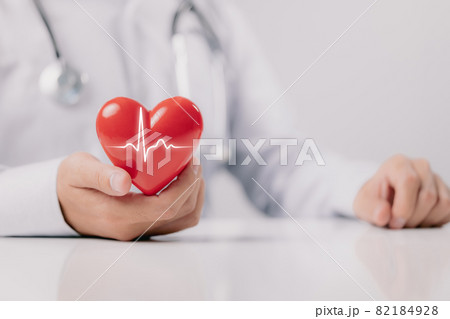 The doctor is holding and showing a red heart with life graph on white background. 82184928