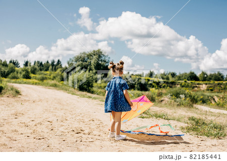 A little girl is flying a kite on a field road outside the city. Childhood, joy, care 82185441
