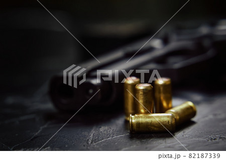 Pistol with cartridges on black concrete table. Pistol with cartridges on black concrete table. 82187339