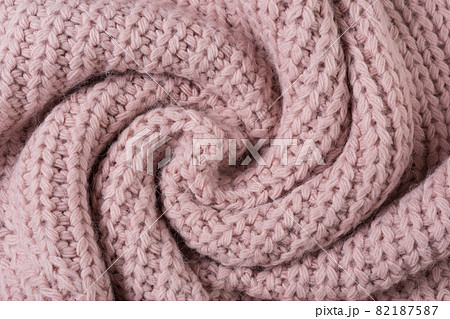 knitted fabric of large knit, pink pastel color, twisted in a circle, like a snail knitted fabric of large knit, pink pastel color, twisted in a circle, like a snail 82187587
