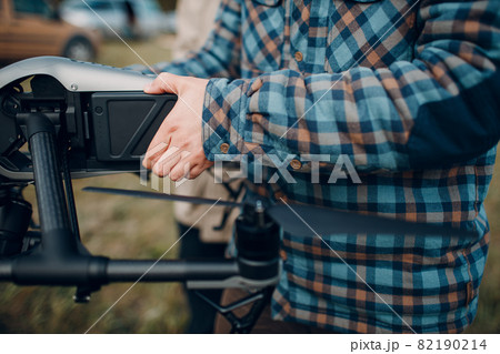 Man pilot checking quadcopter drone before aerial flight and filming. Man pilot checking quadcopter drone before aerial flight and filming. 82190214