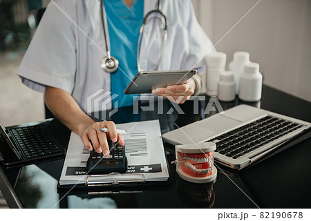 Doctor physician with stethoscope calculate medical fee costs & revenue. practitioner use calculator at Clinic. 82190678