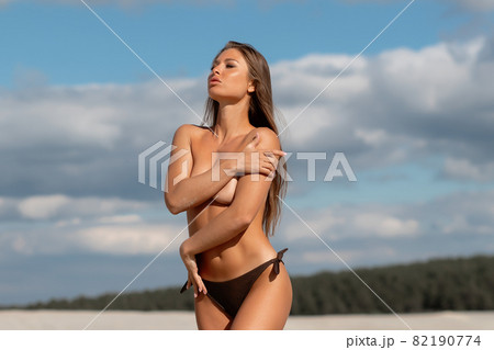 Alluring woman covering breast on beach 82190774