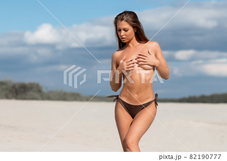 Alluring woman covering breast on beach 82190777