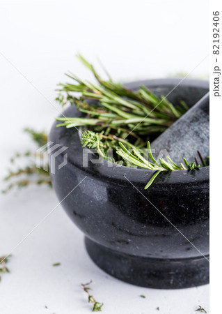 Bunch of fresh herbs in gray stone mortar with pestle Bunch of fresh herbs in gray stone mortar with pestle 82192406