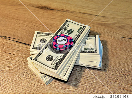 Poker chip for casino game on bundles of dollars.  82195448