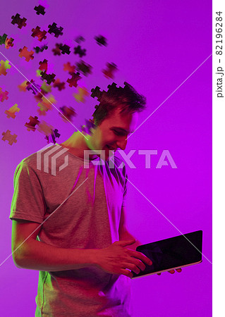 Modern collage of caucasian boy with tablet isolated over purple background. Male head consist of puzzle pieces. 82196284