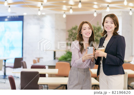 スマホを見ながら談笑する若い女性 82196620