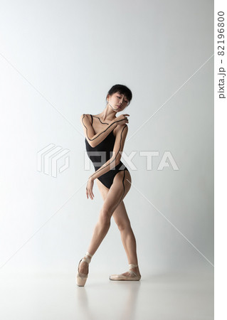Young and graceful ballet dancer, ballerina dancing isolated on light gray studio background. Art, motion, action, flexibility, inspiration concept. Young and graceful ballet dancer, ballerina dancing isolated on light gray studio background. Art, motion, action, flexibility, inspiration concept. 82196800