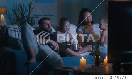 Diverse family watching movie in dark living room 82197732