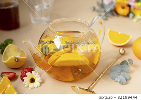 Colorful fruit tea in glass tea pot with fresh fruit slices and strawberries. Colorful fruit tea in glass tea pot with fresh fruit slices and strawberries. 82199444