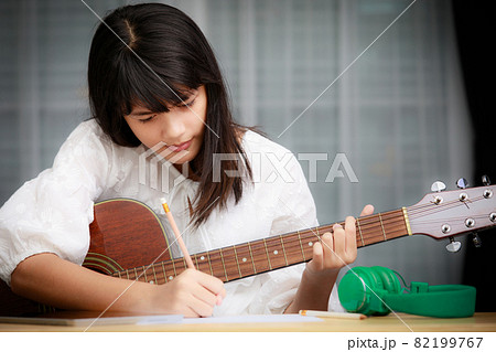 Young girl playing guitar and compose music Young girl playing guitar and compose music 82199767