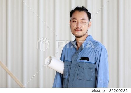 Portrait of male engineer with self-confidense and friendly manner, holding roll paper in hand Portrait of male engineer with self-confidense and friendly manner, holding roll paper in hand 82200285