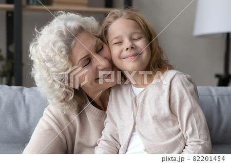 Affectionate old grandmother cuddling little grandchild at home. 82201454