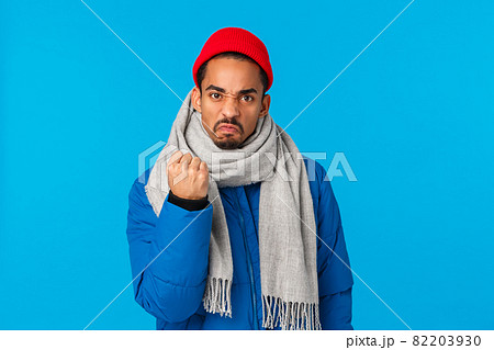 Angry, mad guy threatening person shaking fist at someone on streets. Outraged pissed-off african american man saying i will show you, frowning grimacing and warning you, blue background 82203930