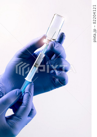Vaccination from coronavirus Covid-19 concept with doctor's hands wearin protective gloves, filling syringe of liquid medication. Vaccination from coronavirus Covid-19 concept with doctor's hands wearin protective gloves, filling syringe of liquid medication. 82204121