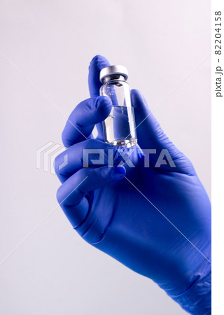 Vaccination from coronavirus Covid-19 concept with doctor's hands wearin protective gloves, holding botle of liquid medication. Vaccination from coronavirus Covid-19 concept with doctor's hands wearin protective gloves, holding botle of liquid medication. 82204158