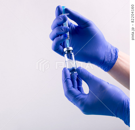 Vaccination from coronavirus Covid-19 concept with doctor's hands wearin protective gloves, filling syringe of liquid medication. Vaccination from coronavirus Covid-19 concept with doctor's hands wearin protective gloves, filling syringe of liquid medication. 82204160
