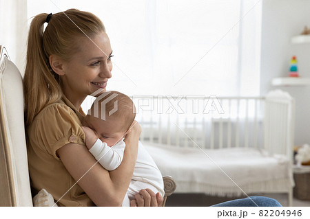Happy young new mom holding sleepy baby in arms Happy young new mom holding sleepy baby in arms 82204946