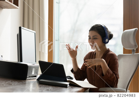Young indian female in earphones provide virtual training using touchpad Young indian female in earphones provide virtual training using touchpad 82204983