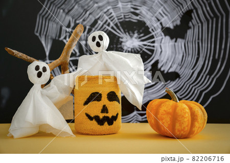 Two ghosts, pumpkin, candlestick with scary Halloween grimace on background of cobweb. Halloween Concept Two ghosts, pumpkin, candlestick with scary Halloween grimace on background of cobweb. Halloween Concept 82206716