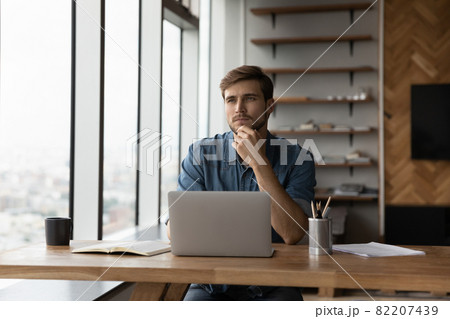 Pensive male employee work on laptop thinking 82207439