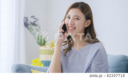 家でスマホで通話する若い女性 82207718