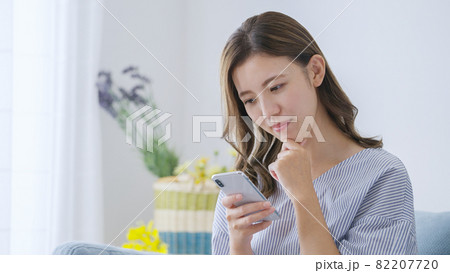 家でスマホを操作する若い女性 82207720