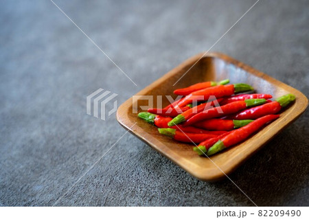 暗い背景で木の器に入った赤唐辛子 暗い背景で木の器に入った赤唐辛子 82209490