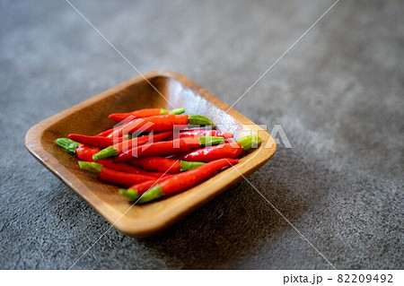暗い背景で木の器に入った赤唐辛子 暗い背景で木の器に入った赤唐辛子 82209492