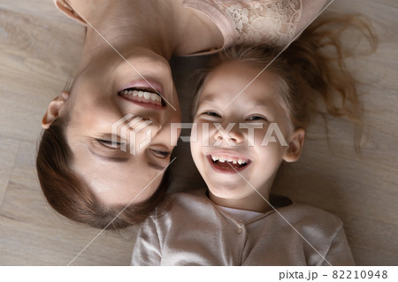 Happy young mother lying on floor with small kid. Happy young mother lying on floor with small kid. 82210948