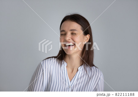 Head shot laughing excited young woman on grey background Head shot laughing excited young woman on grey background 82211188
