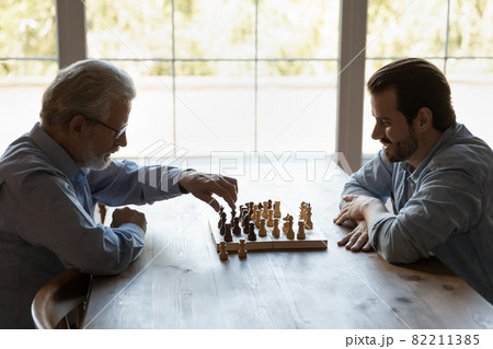 Side view young man with mature father playing chess together 82211385