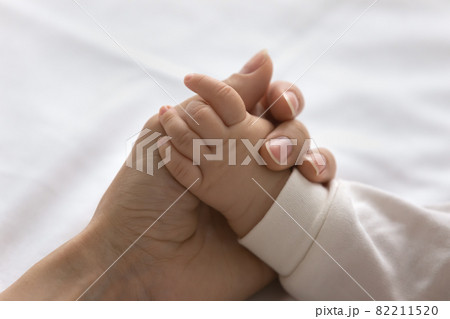 Young mom touching little palm of little baby 82211520