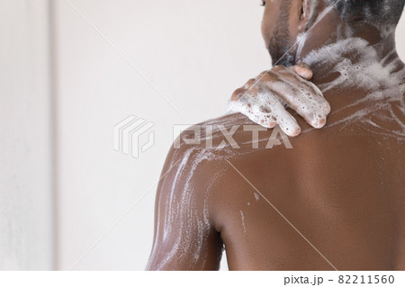 African man washes in shower, back and shoulder view 82211560